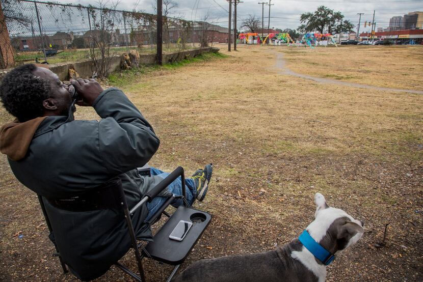 Charlie Alexander Jr., who is homeless, took a sip of beer on Dec. 12 while his dog King sat...