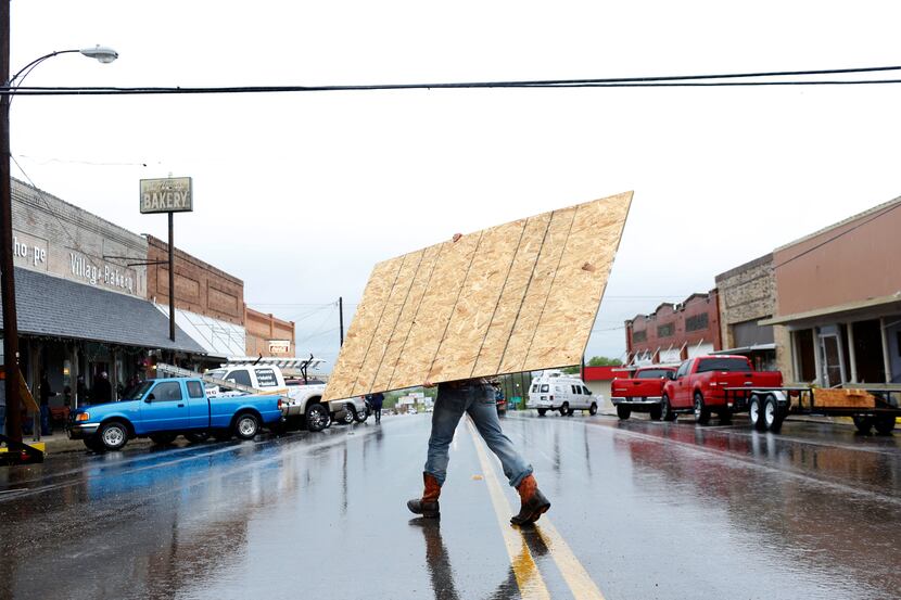Workers carry plywood to cover damaged windows in West, Texas where a fertilizer plant...