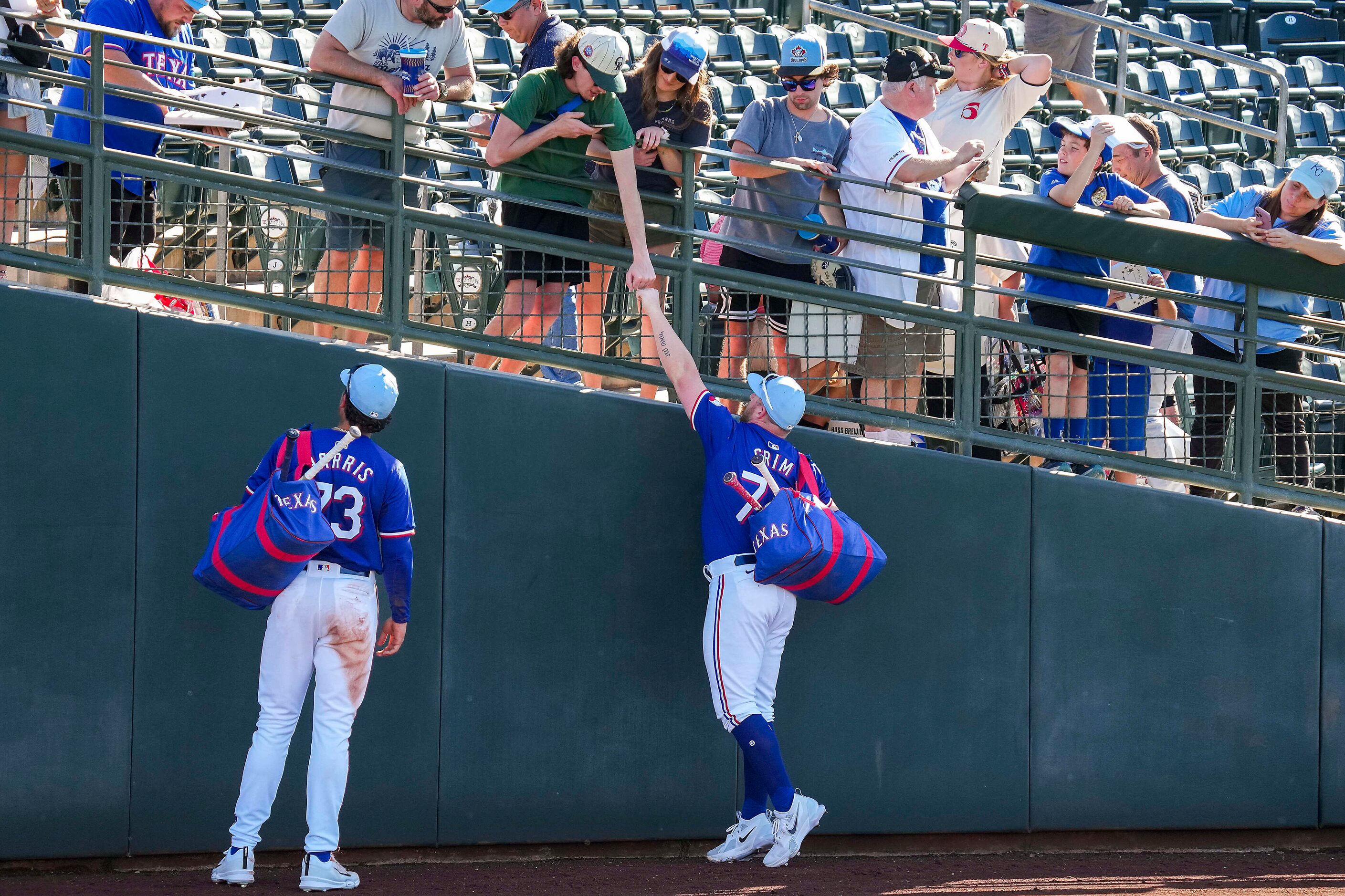 Texas Rangers infielder Blaine Crim fist bumps a fan as he signs autographs with outfielder...