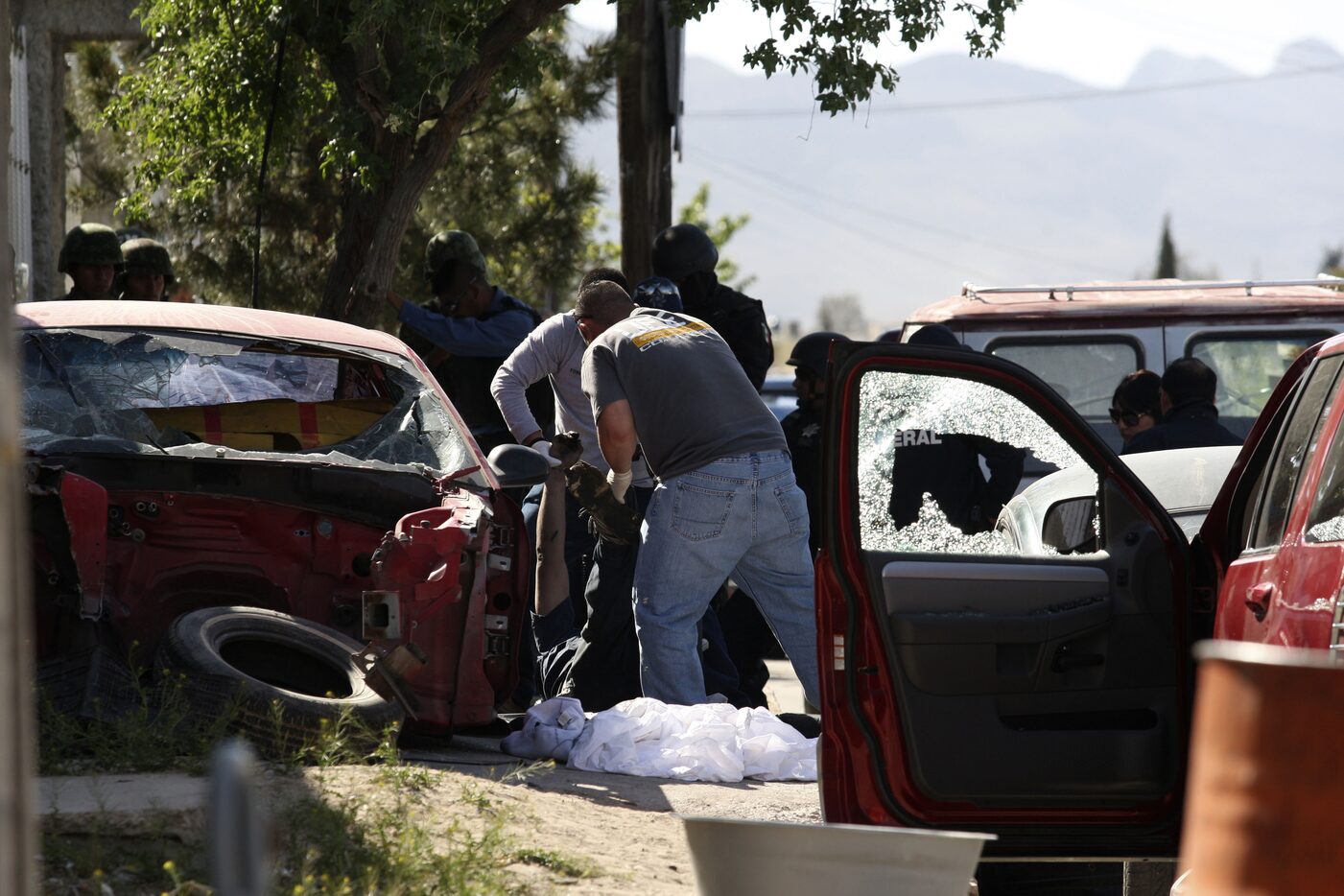 Mexican police carry a dead man from a garage in Ciudad Juarez where five corpses were found...