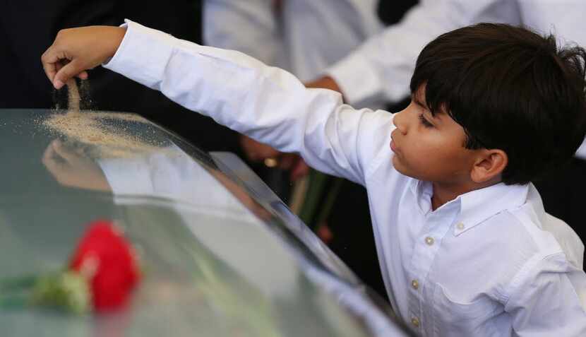 Eight-year-old Nicholas Garcia placed dirt on the casket of his grandfather Felix Lozada at...