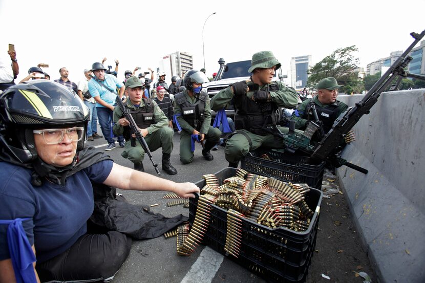 FILE - In this April 30, 2019 file photo, an anti-government protester sits by ammunition...