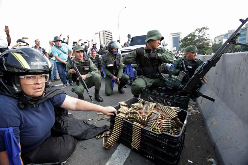 FILE - In this April 30, 2019 file photo, an anti-government protester sits by ammunition...
