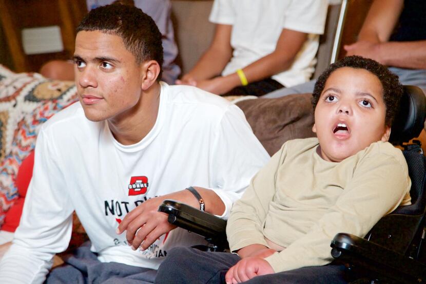 
Caleb Evans, 17, watches Monday Night Football with his brother Nathaniel, 8, at their home...