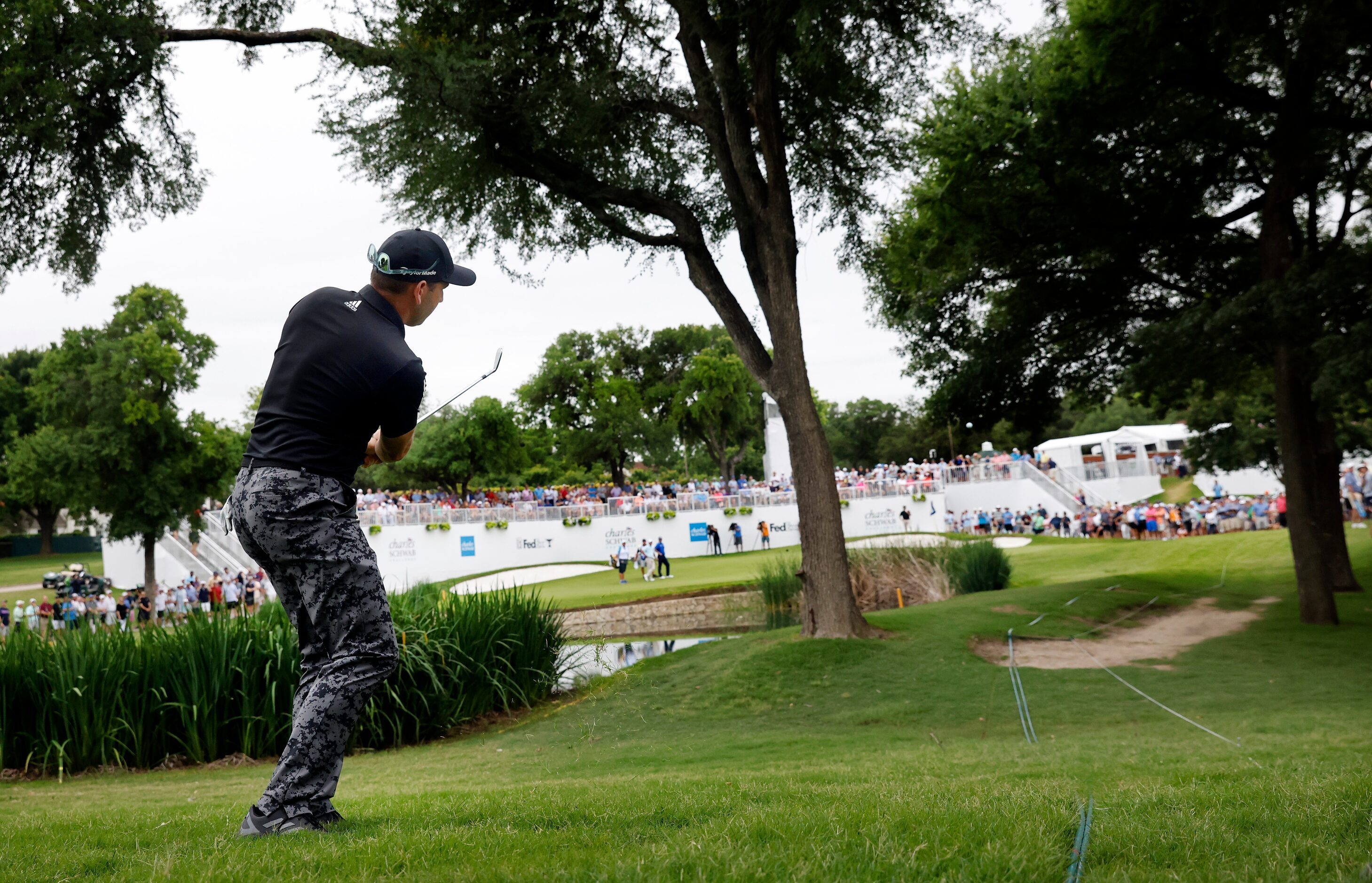 Professional golfer Sergio Garcia hits his approach shot under a tree and along the green...