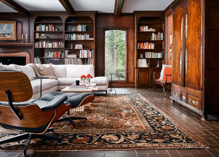 Living room with brown floors, wood paneling on the walls, an antique armoire and a...