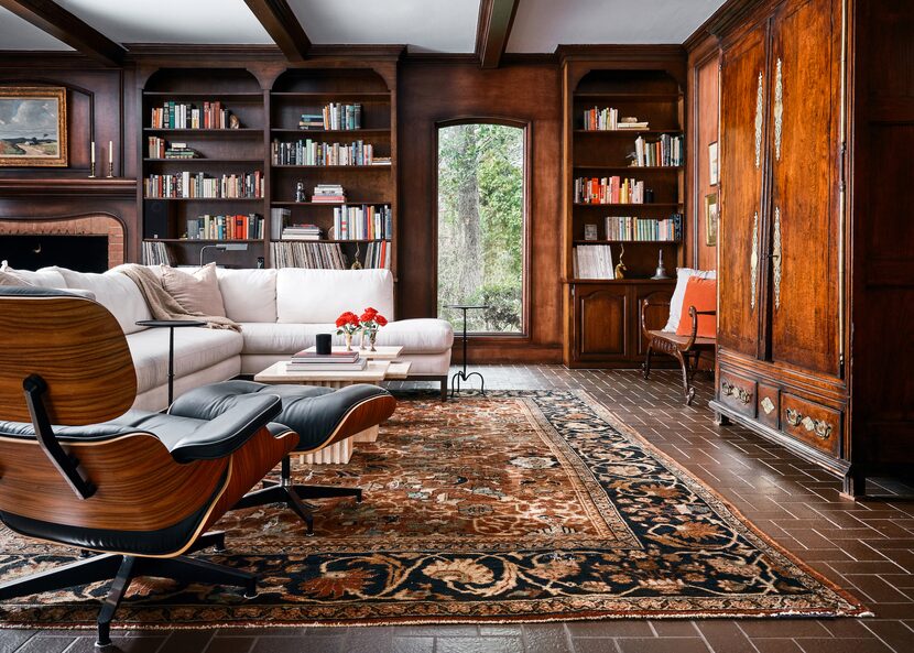 Living room with brown floors, wood paneling on the walls, an antique armoire and a...