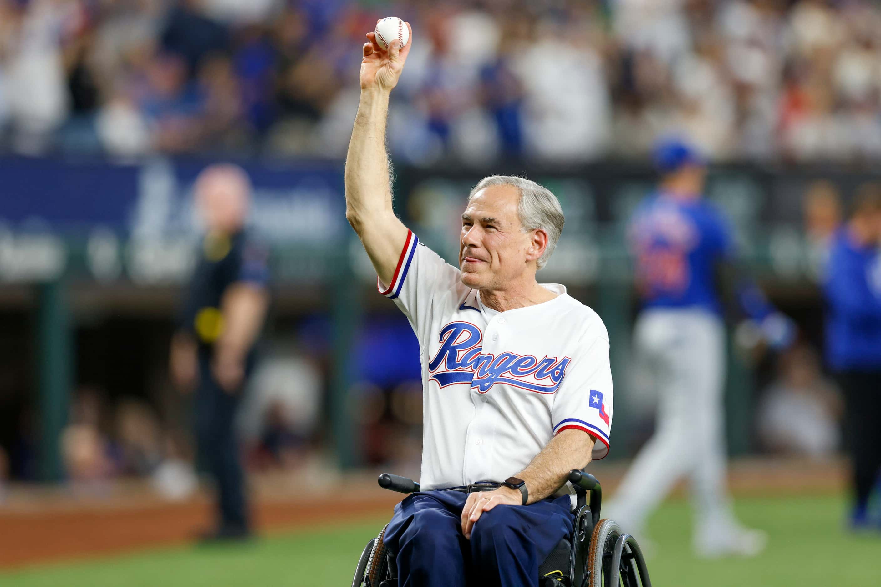 Texas governor Greg Abbott raises the ceremonial first pitch baseball before the Texas...