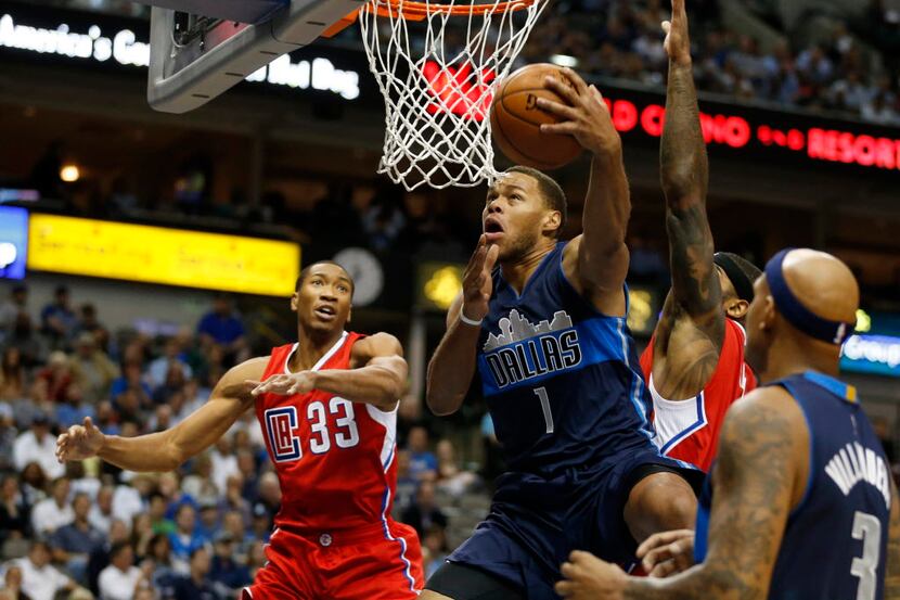 Dallas Mavericks guard Justin Anderson (1) goes up and around for a basket as he is defended...