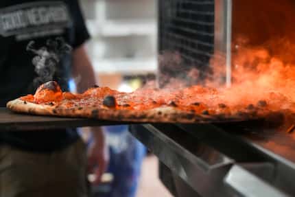 Culinary director David Peña pulls a hot pizza out of the oven at Fortunate Son in Garland.