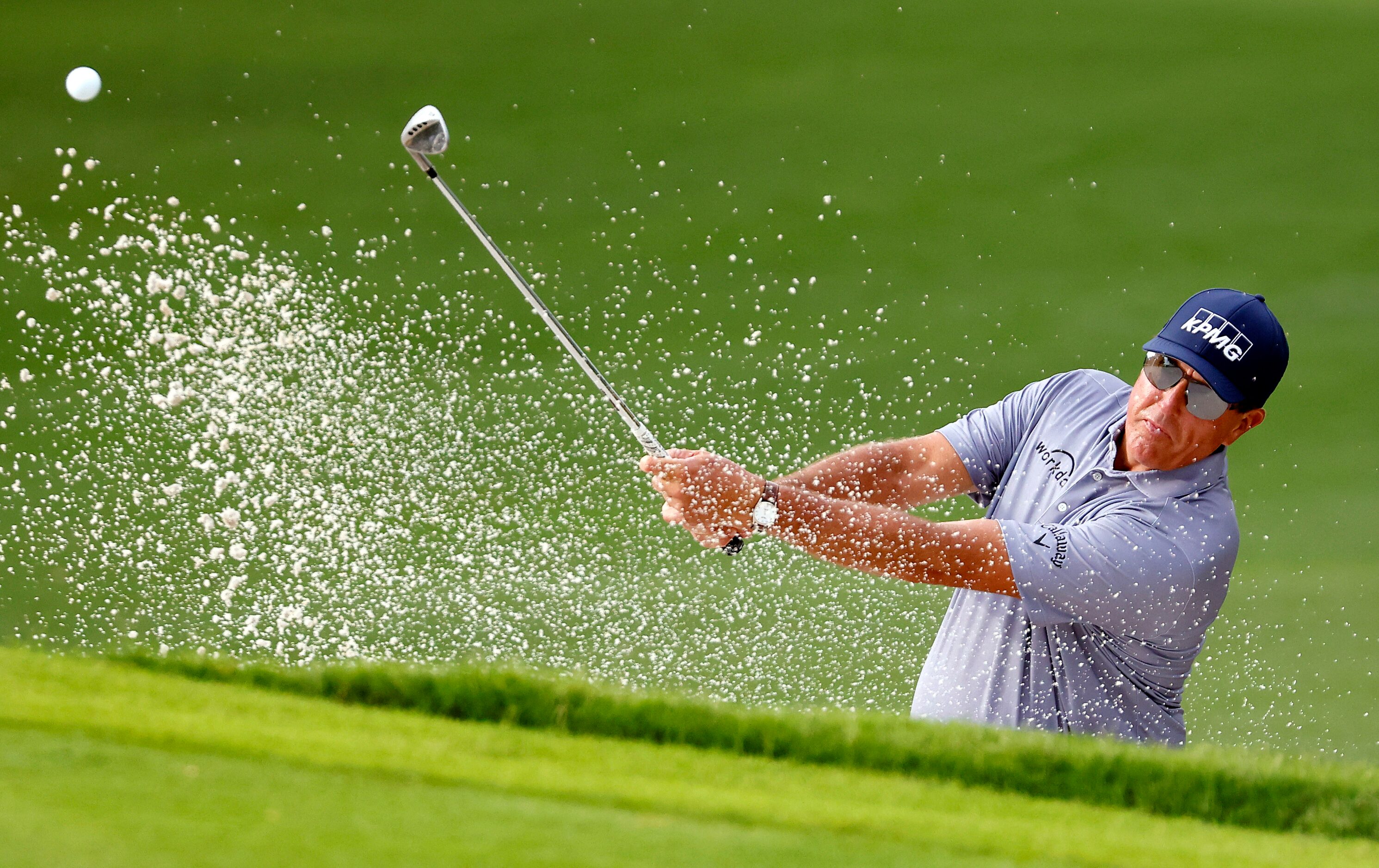 Professional golfer Phil Mickelson hits out of the  No. 12 green side bunker during round...