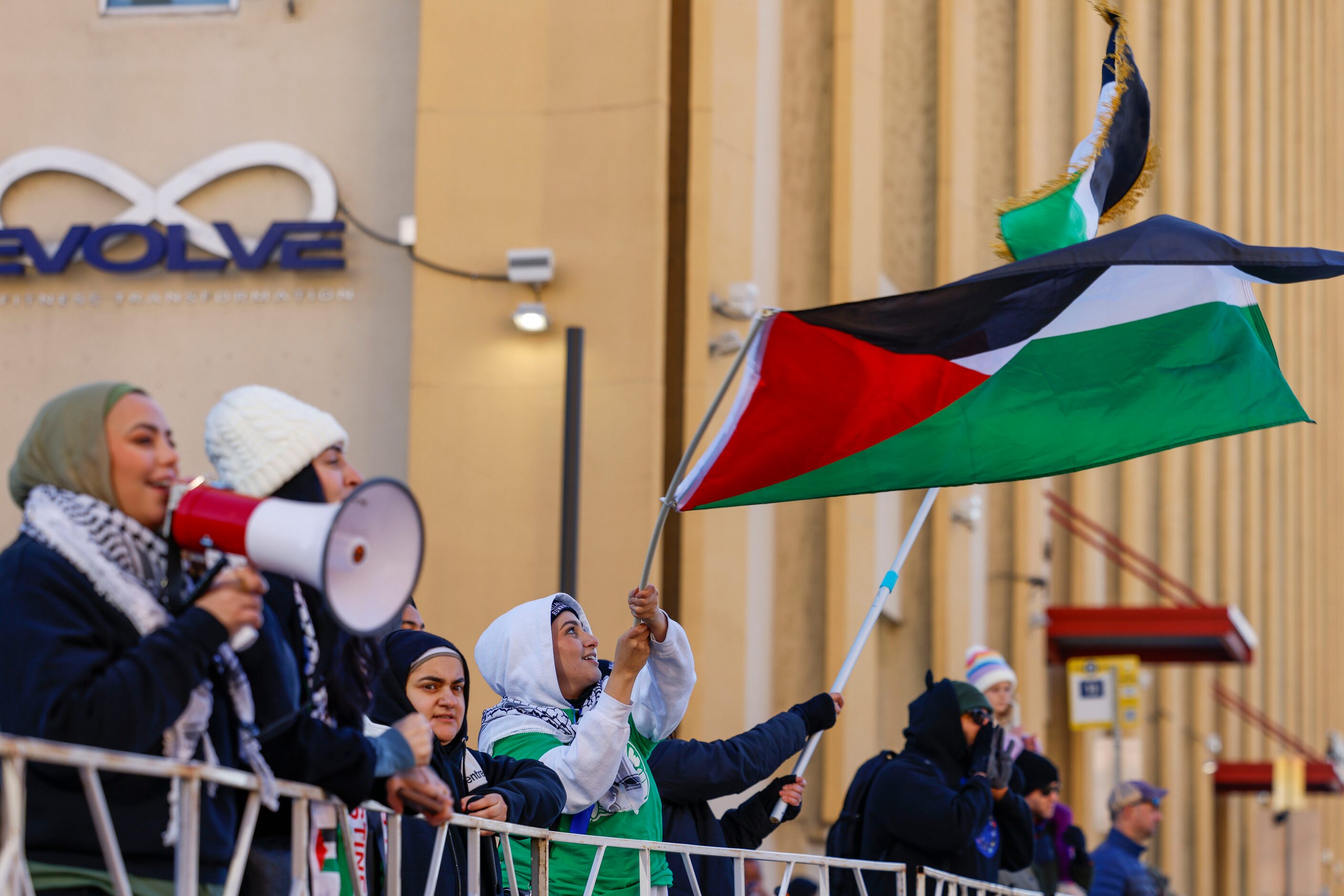 Dallas Muslim Running Club members waving Palestinian flag cheer for the runners during 2023...