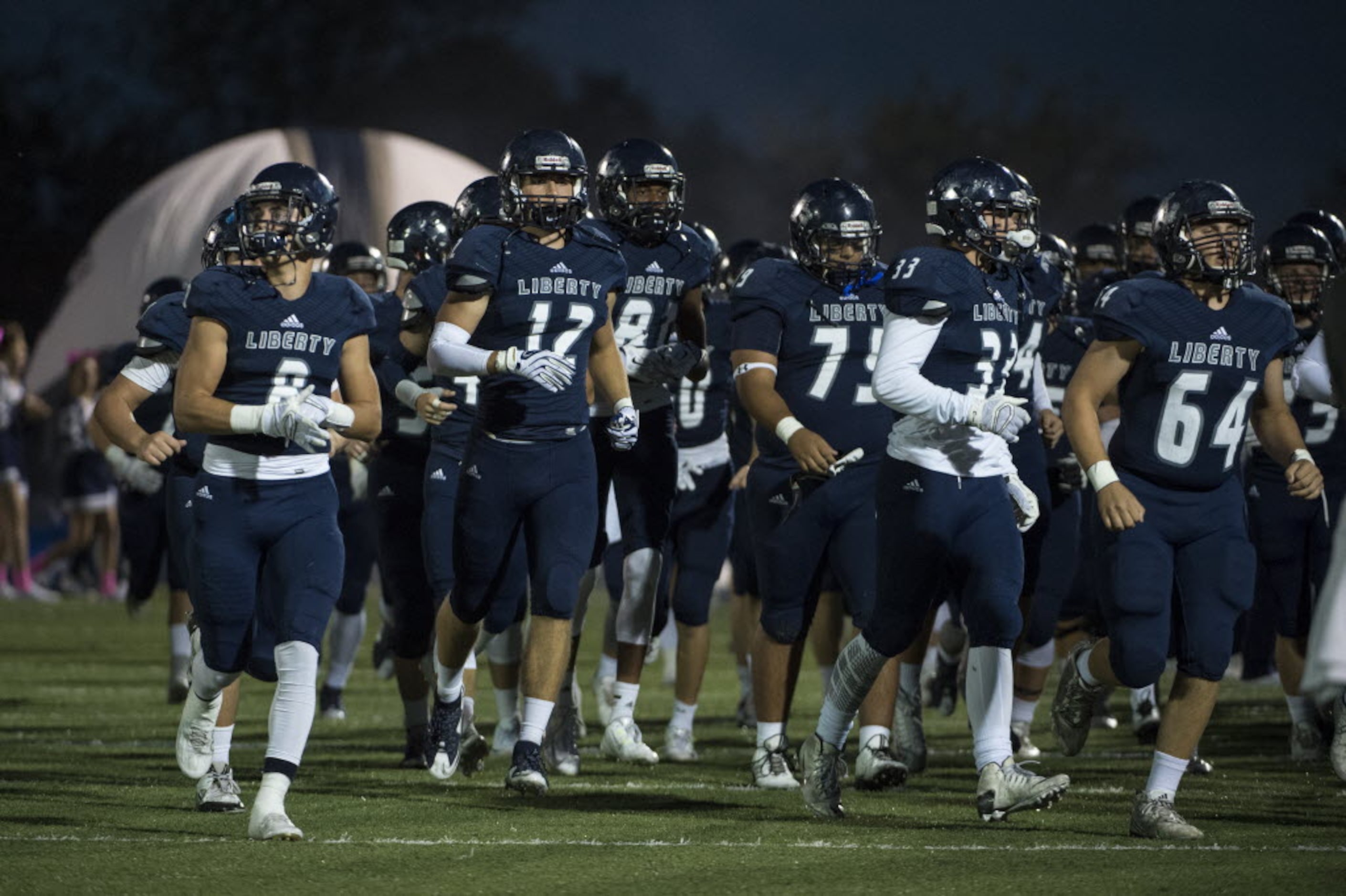 The Liberty Christian Warriors run onto the field before a high school football game with...