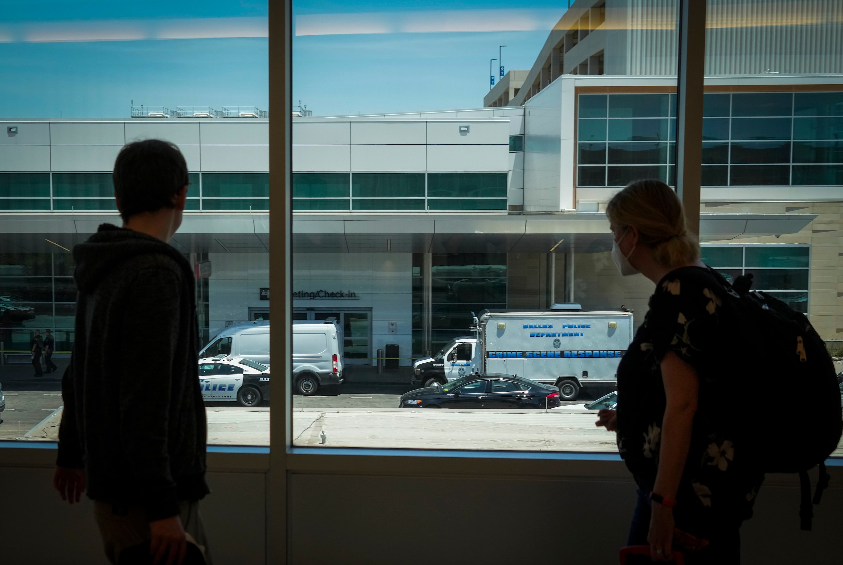 Passengers look out as Dallas police investigate the scene of a shooting while waiting to...