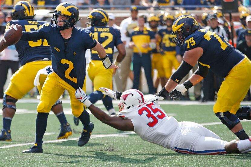 Southern Methodist Mustangs defensive end Delontae Scott (35) tries to hang on to Michigan...