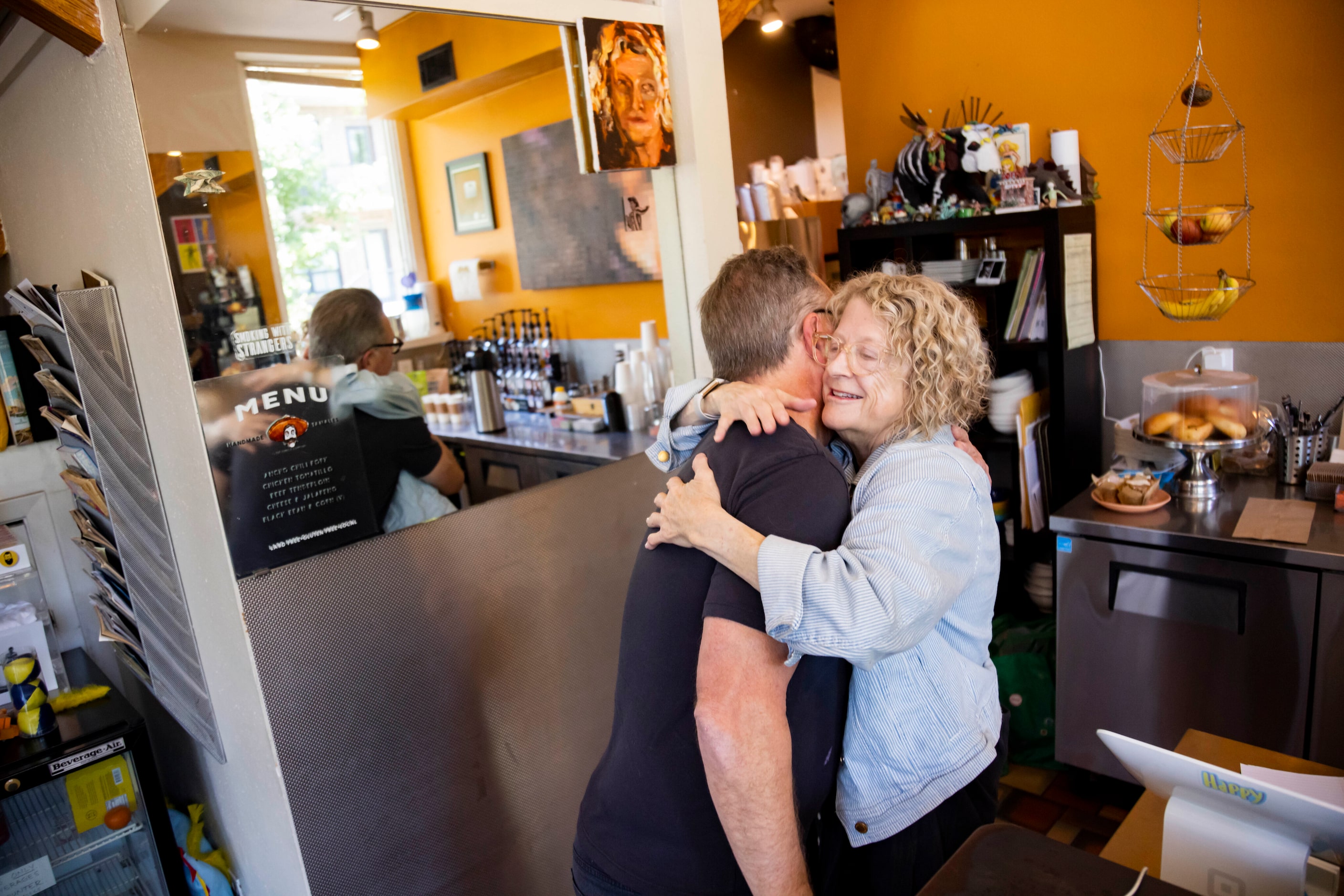 Liz Davis, owner of Murray Street Coffee Shop, hugs Brandt Wood, former owner of Trees, The...