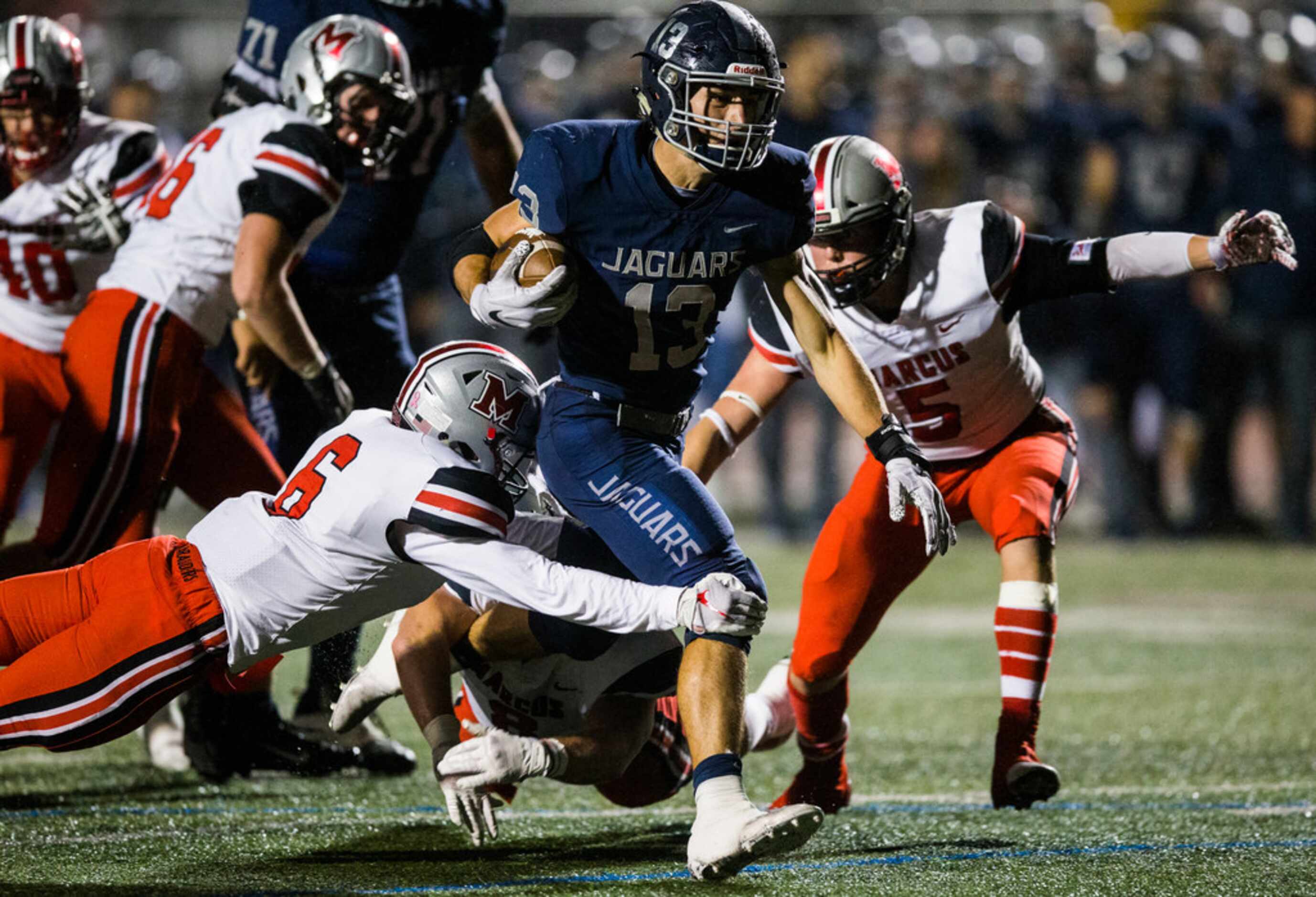 Flower Mound running back Pierce Hudgens (13) is tripped up by Flower Mound Marcus defensive...