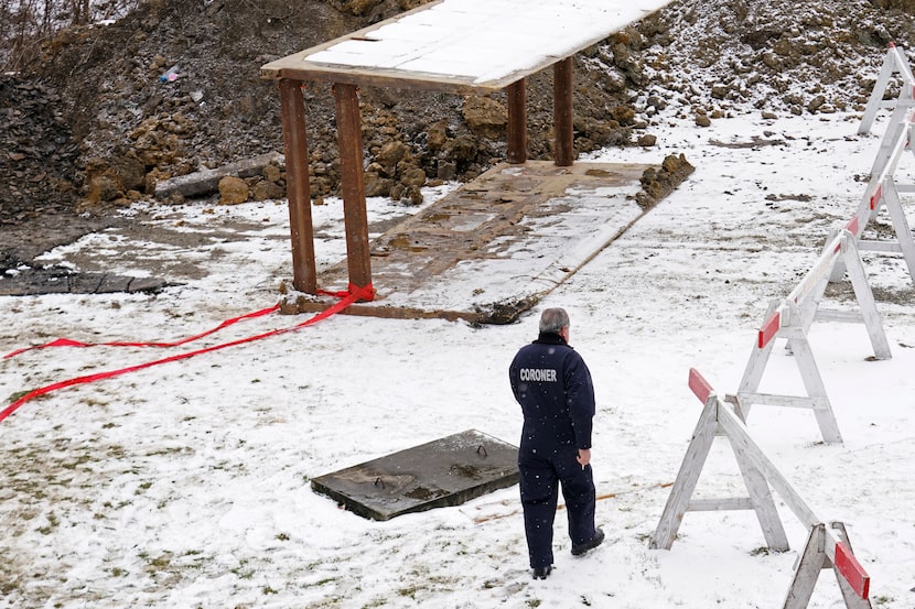 Un empleado de la oficina forense trabaja en la zona cerca de un socavón donde hace cuatro...