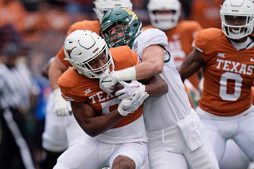 Texas running back Bijan Robinson, left, is hit by Baylor linebacker Dillon Doyle, right, on...