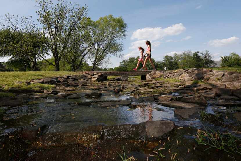 Two girls walk over a creek at the Colleyville Nature Center on April 23, 2014.