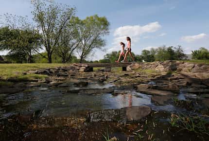 Two girls walk over a creek at the Colleyville Nature Center on April 23, 2014.  