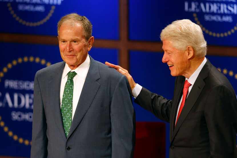 Former President George W. Bush and former President Bill Clinton share a laugh as they...