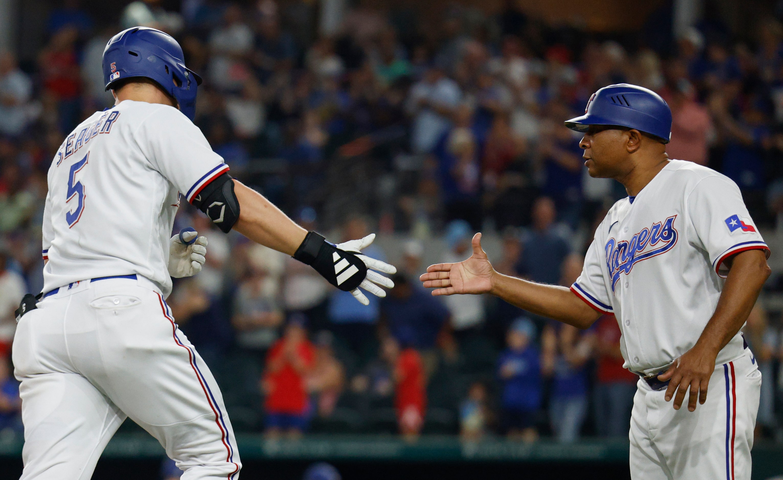 Texas Rangers shortstop Corey Seager (5) high-fives Texas Rangers third base coach Tony...