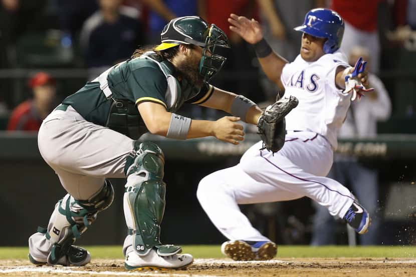Texas' Adrian Beltre slides home safely with a Rangers run in the fourth inning as A's...