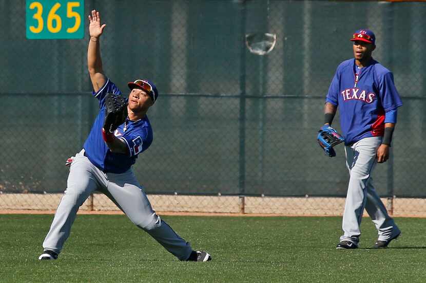 Texas outfielders Michael Choice, left, and Engel Beltre work at playing a fly ball in the...