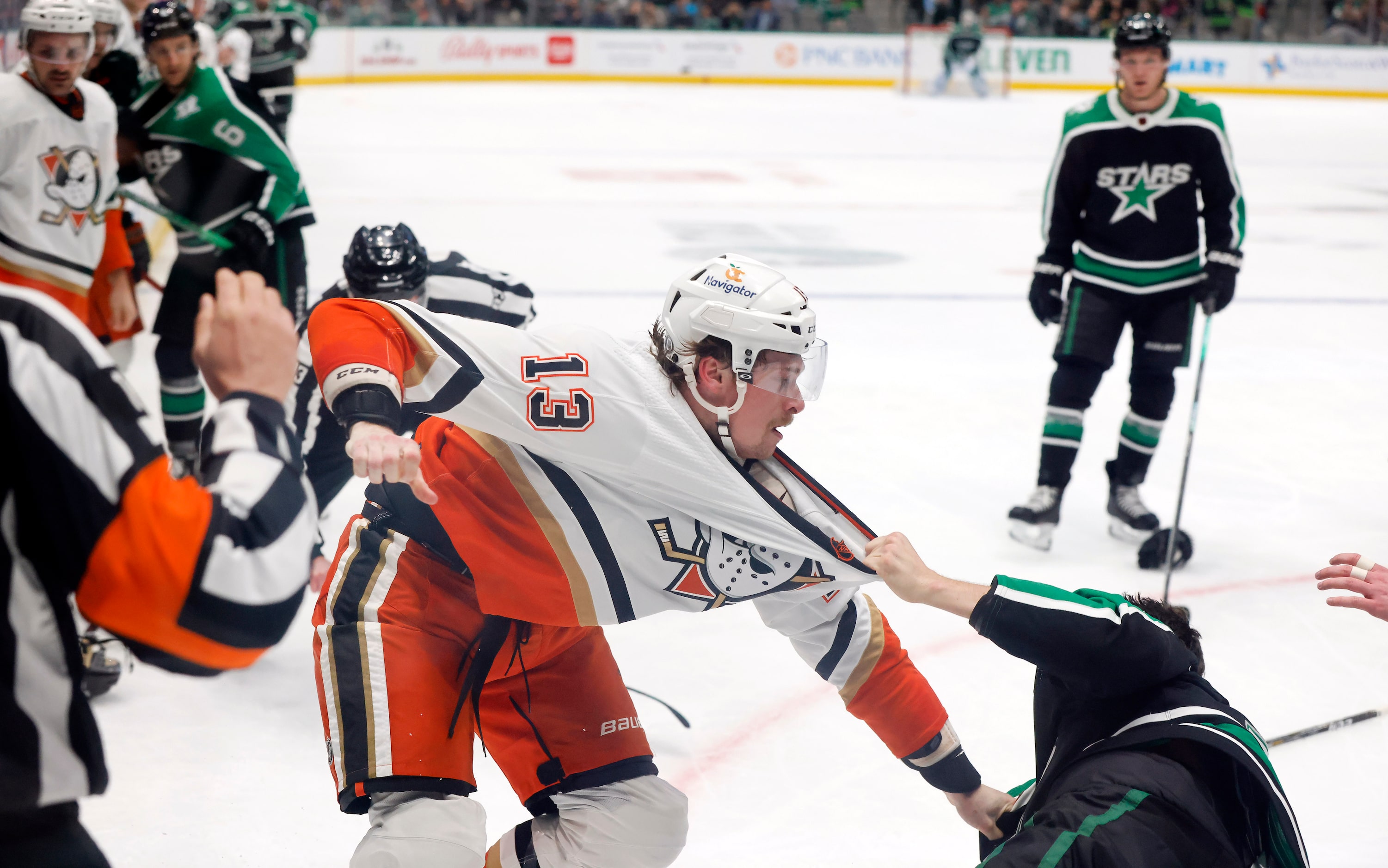 Anaheim Ducks defenseman Simon Benoit (13) is dragged to the ice by Dallas Stars left wing...