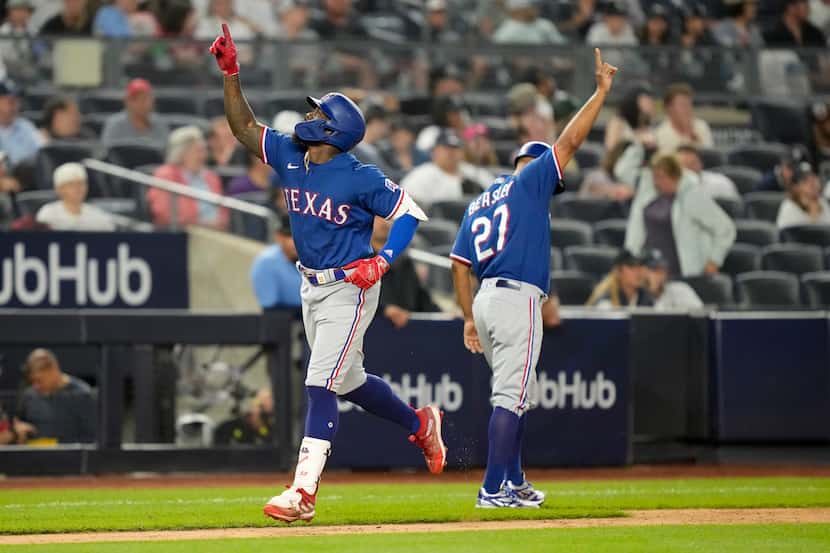 Texas Rangers' Adolis Garcia, left, celebrates as he runs the bases after hitting a go-ahead...