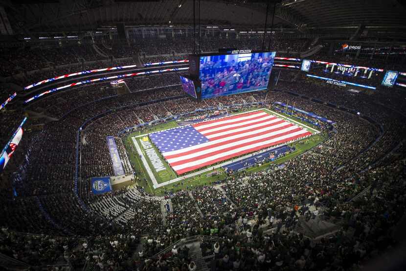 A large American flag covers the field during playing of the national anthem before the...