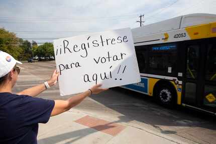 League of Women Voters of Dallas volunteer, Edna Arratia, holds up a sign to promote voter...