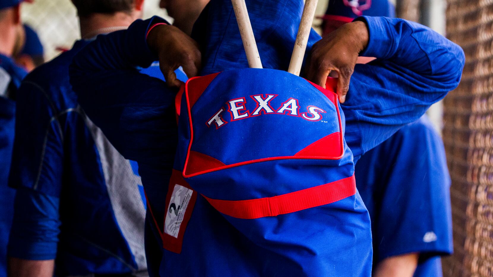 Texas Rangers players pack up their things in the dugout as rain falls during a spring...