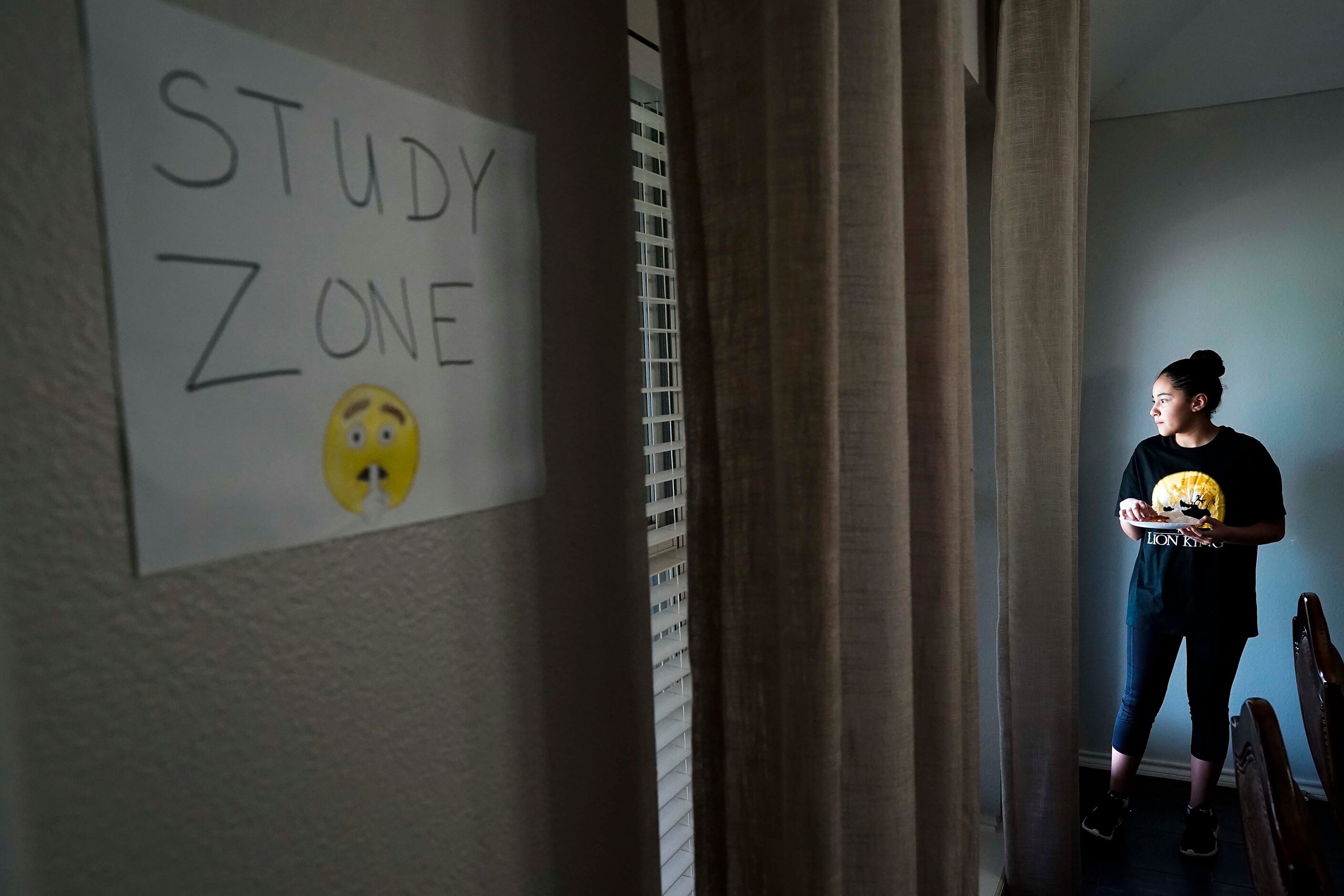 Karla Cabrera, 11, gazes out while eating her lunch at the familyÕs home in Grand Prairie on...