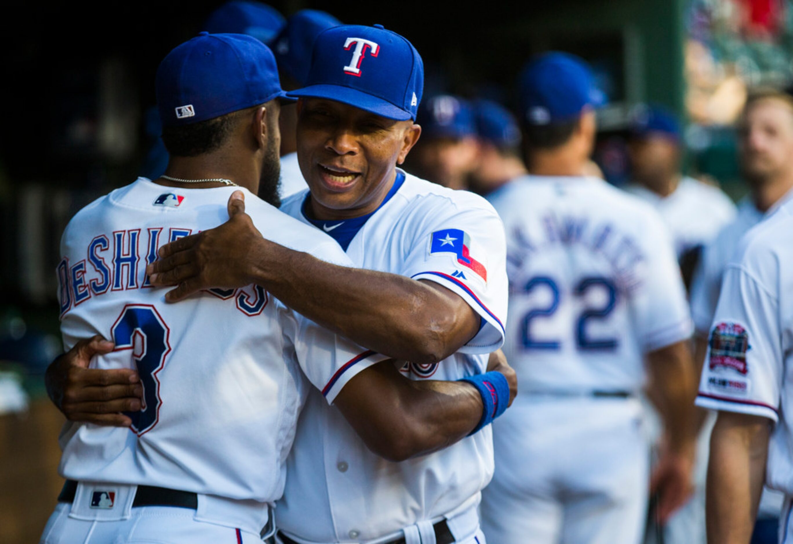 Texas Rangers third base coach Tony Beasley (37) hugs center fielder Delino DeShields (3) in...