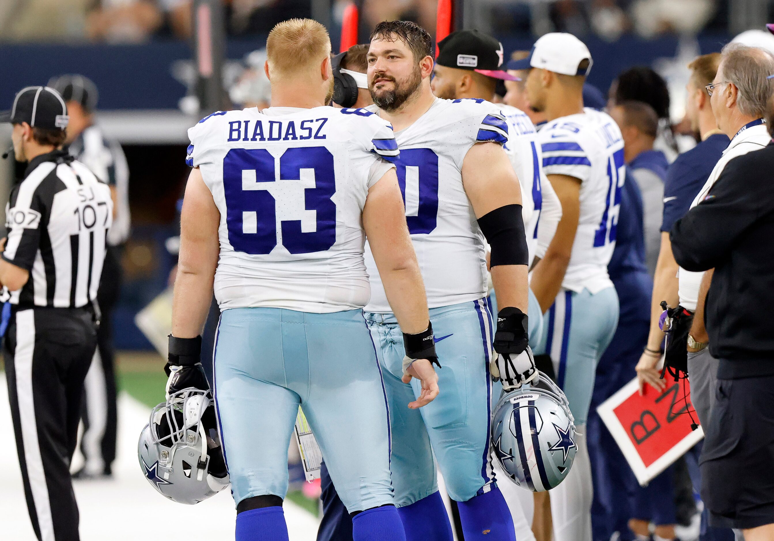 Dallas Cowboys guard Zack Martin (70) visits with center Tyler Biadasz (63) on the sideline...