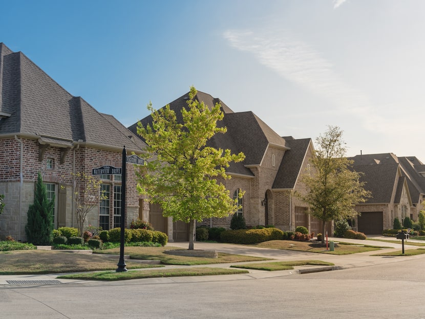 Upscale neighborhood with two-story homes and small trees against blue sky