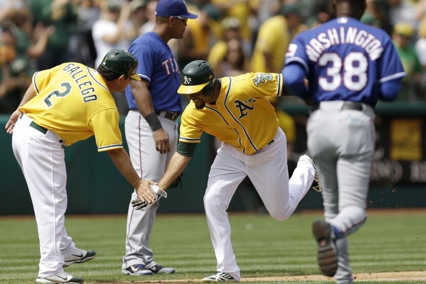 Oakland Athletics' Coco Crisp, center, is congratulated by third base coach Mike Gallego (2)...