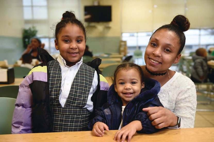 A family of three smiles for a posed photo at Union Gospel Mission Dallas.