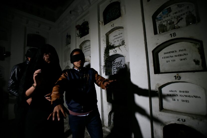 Blindfolded tourists walk through El Tejar cemetery in Quito, Ecuador.