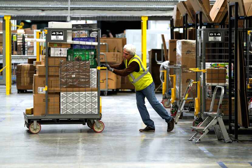 A worker moves merchandise at the Amazon fulfillment center in Aurora, Colo. The...