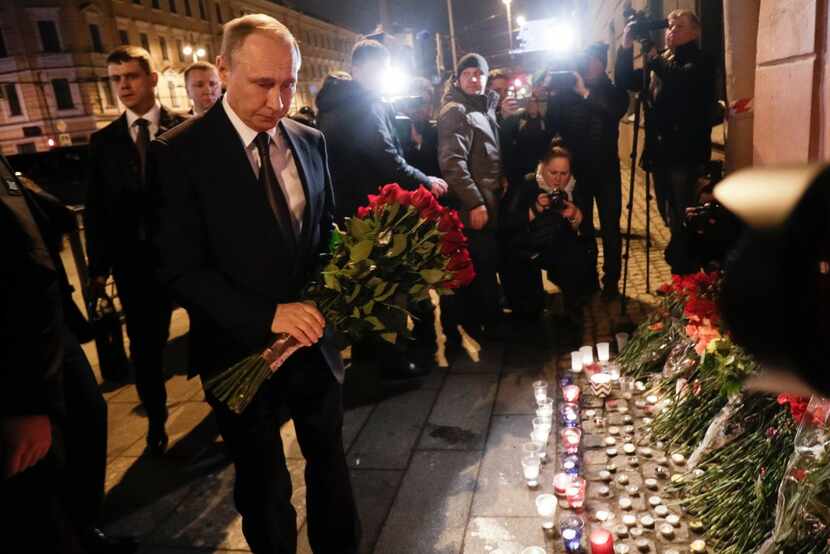 Russian President Vladimir Putin, left, lays flowers at a place near the Tekhnologichesky...
