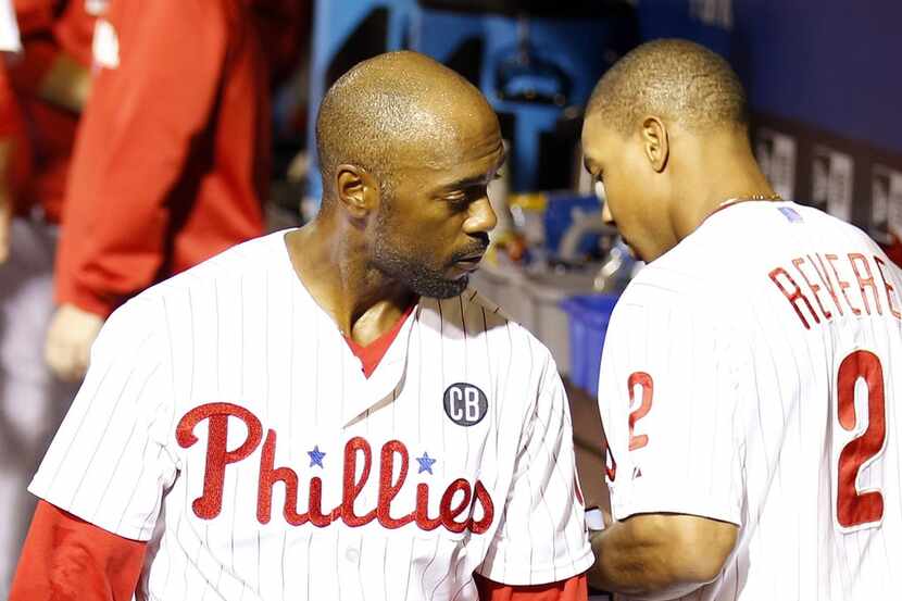 Philadelphia Phillies' Jimmy Rollins walks past teammate Ben Revere after Rollins left their...