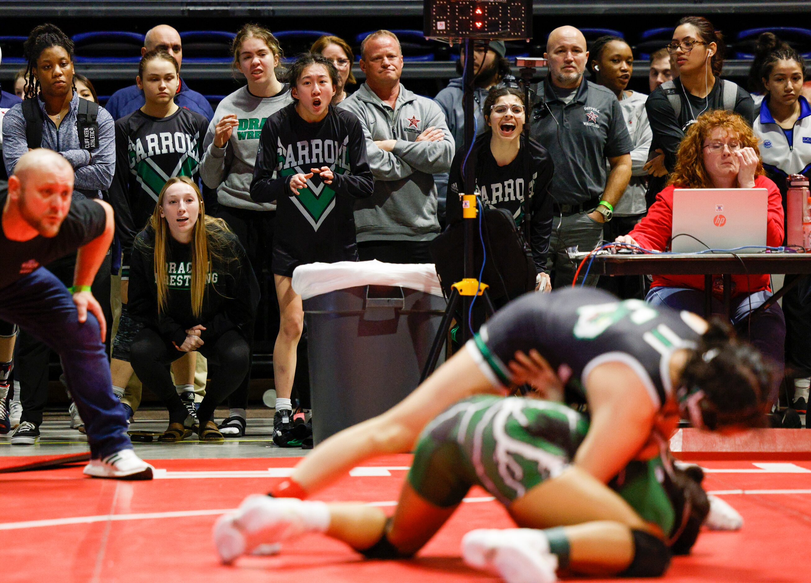 Members of the Southlake wrestling team watch as Bayley Trang of Southlake Carroll wrestles...