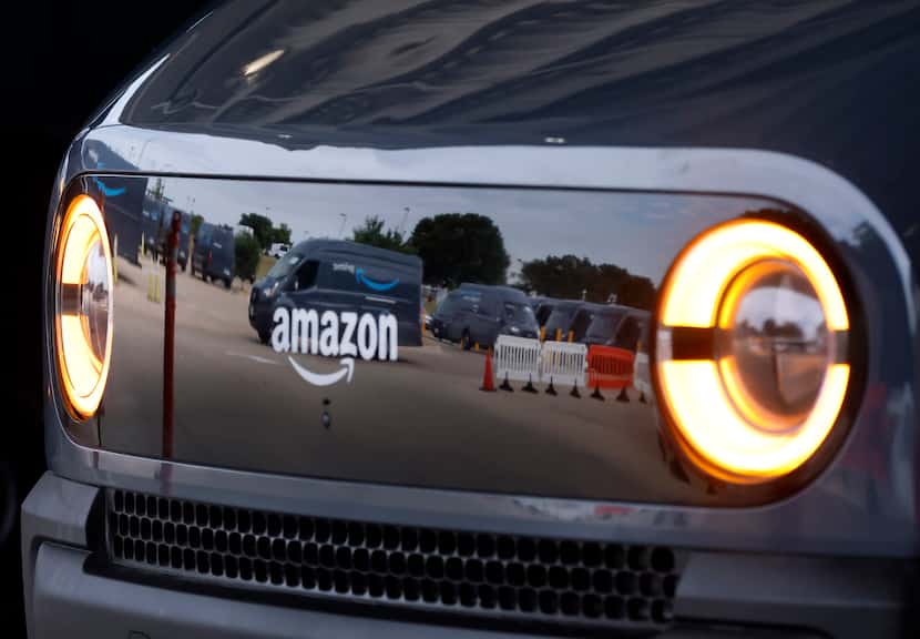 An Amazon Electronic Delivery Vehicle (EDV) is reflected in another as they load their...