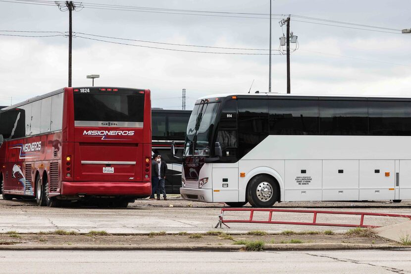 Charter buses and white vans gather at Hotel Street parking lot behind the Kay Bailey...