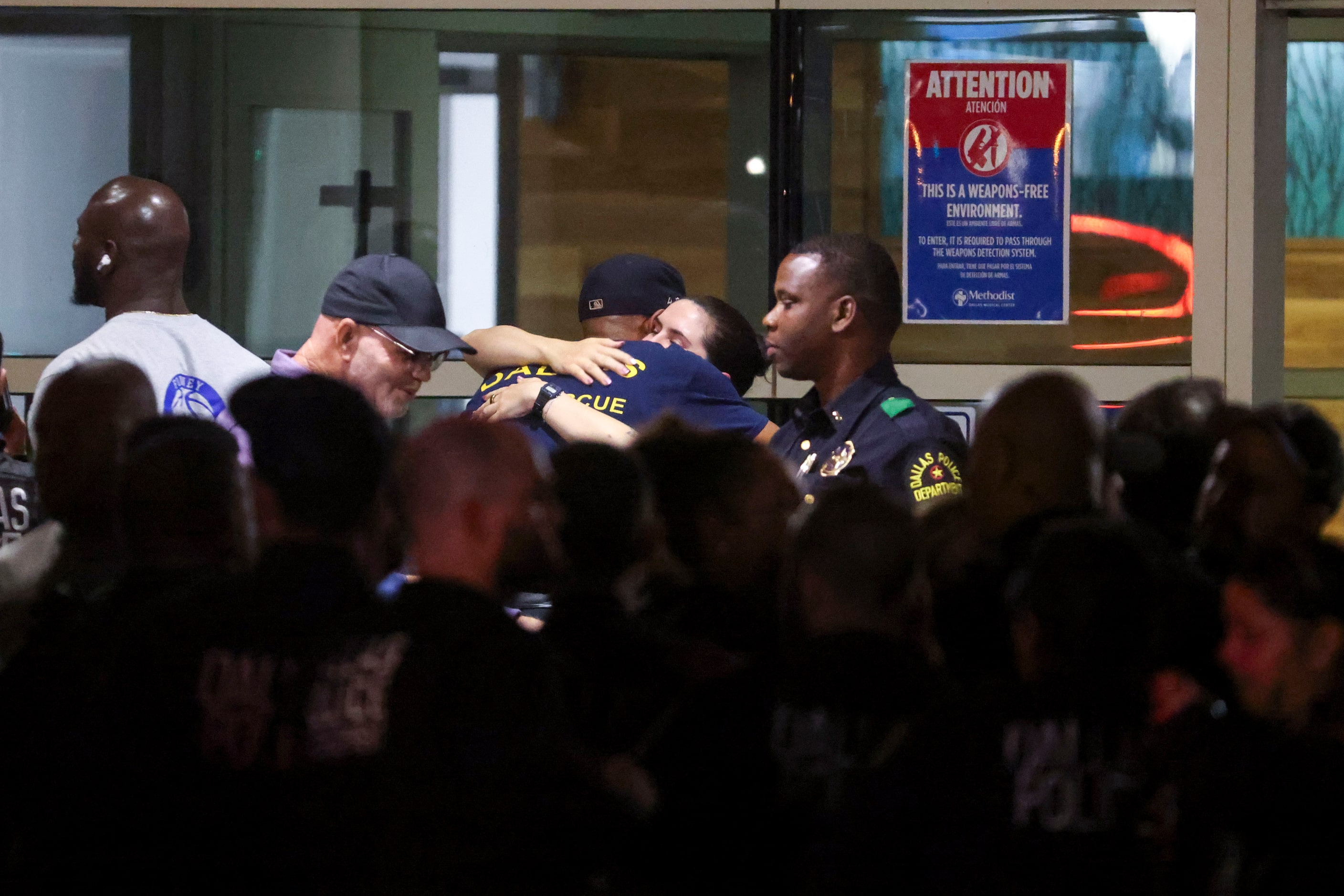 Dallas Police Department and other law enforcement officers comfort each other following a...