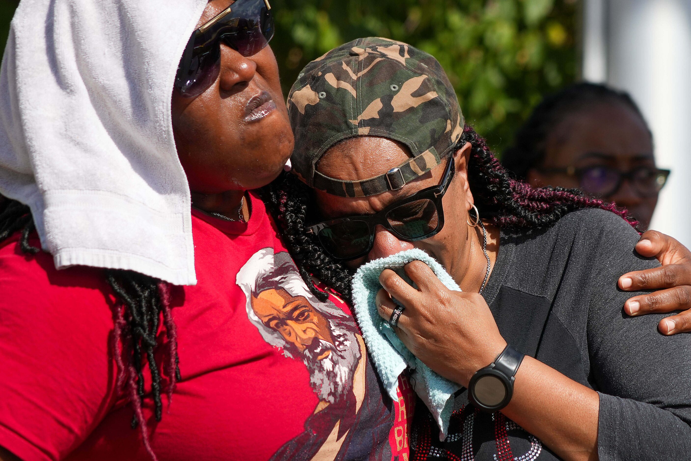 Mourners listen to a speaker during a vigil around a Dallas police patrol car serving as a...