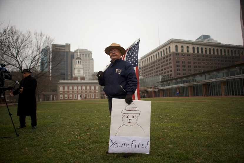 David Fitzpatrick, 64, a park ranger, holds an American flag and a placard stating "You're...